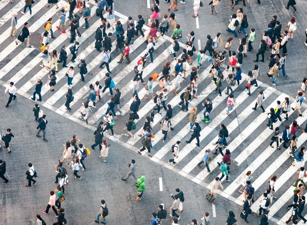 Eine Luftaufnahme eines belebten Fußgängerüberwegs mit Menschen, die in verschiedene Richtungen gehen.